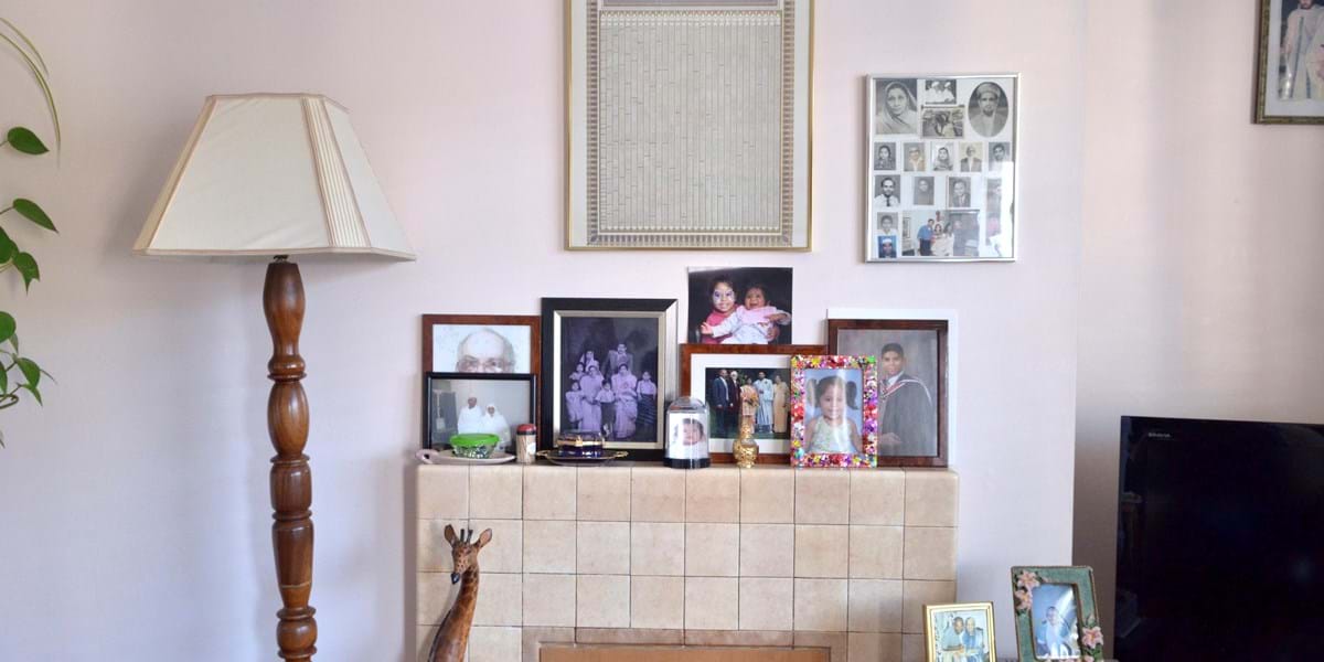 A beige mantelpiece set against a pink wall, decorated with family photos