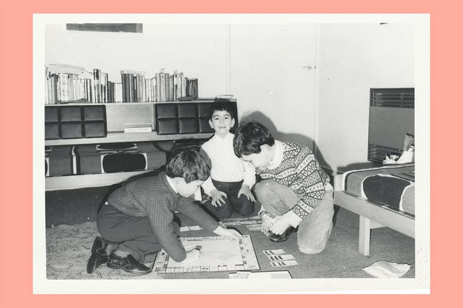 Printed black and white of children playing a board game on the floor