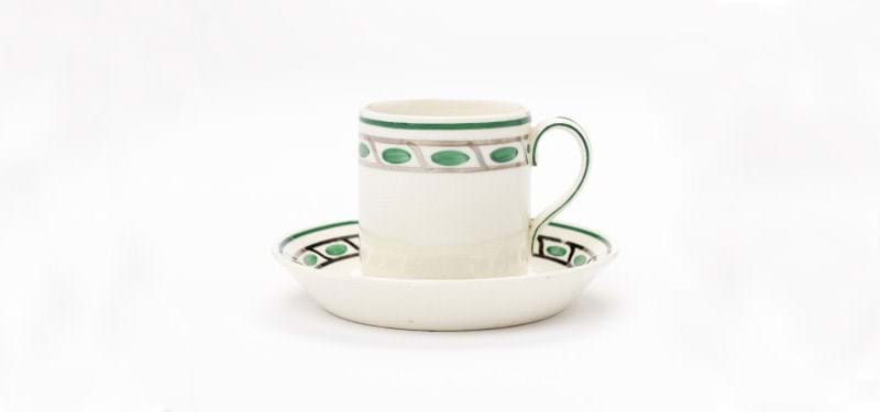 A white porcelain cup and saucer set, with a green patterned trim