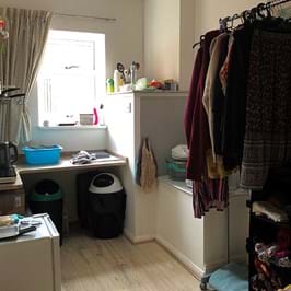 A studio flat with a kettle, small bins and clothes rail