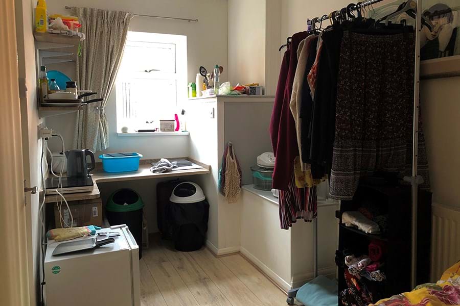 A studio flat with a kettle, small bins and clothes rail