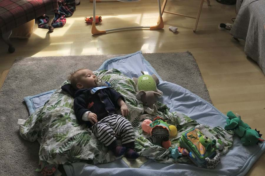 A baby sleeping on pillows and blankets on the floor