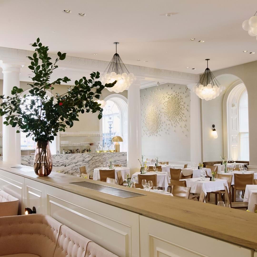 An elegant restaurant with white walls, creative lamps and wooden furniture