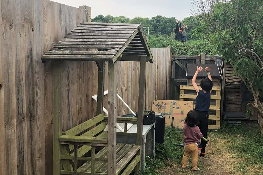 Children and adults waving across a fence