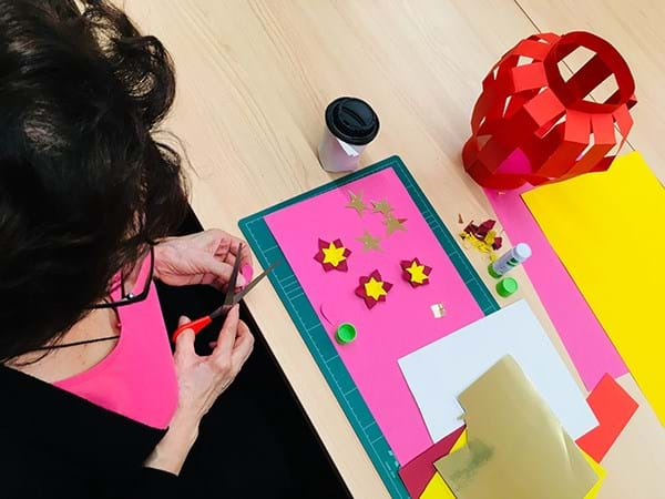 A person cutting out shapes from coloured paper at a desk