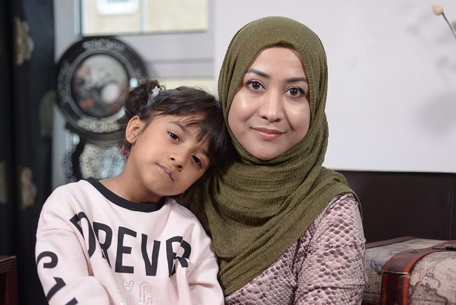 An adult smiling at the camera with a child on their lap