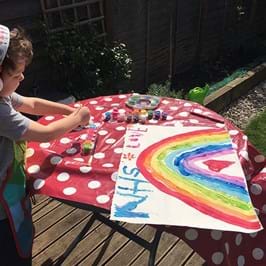 Child in headphones painting a rainbow on a table with red/white polka dot tablecloth