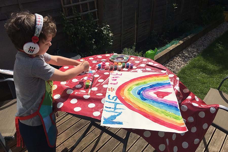 Child in headphones painting a rainbow on a table with red/white polka dot tablecloth