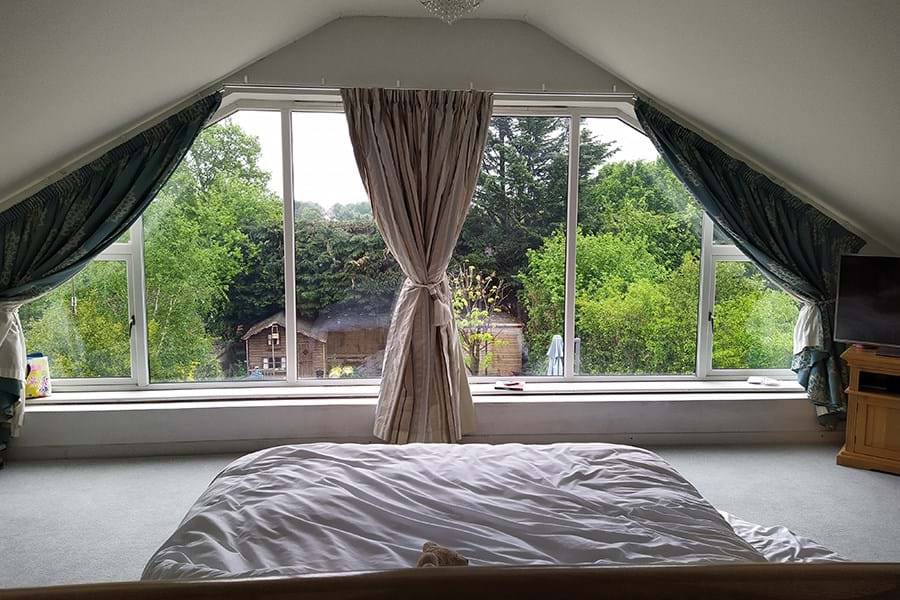 A bed facing a window overlooking a garden.