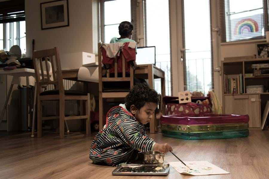 A small child sat on the floor painting a piece of paper 