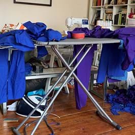 Piles of medical scrubs on top of an ironing board