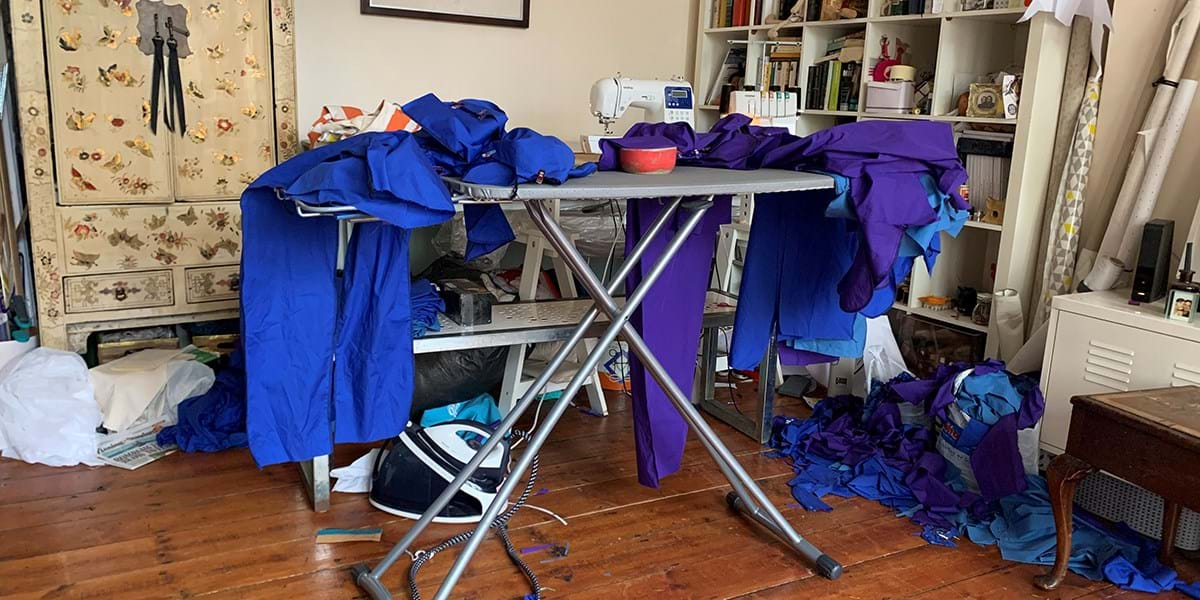 Piles of medical scrubs on top of an ironing board