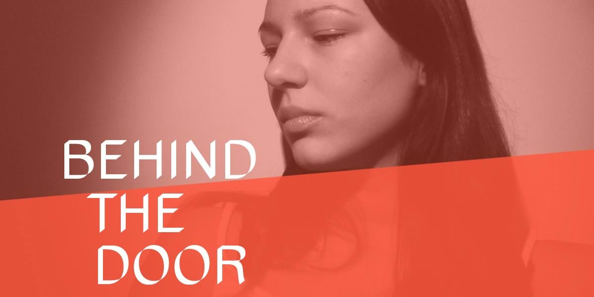 A person looking down, with text overlaid that reads 'behind the door'