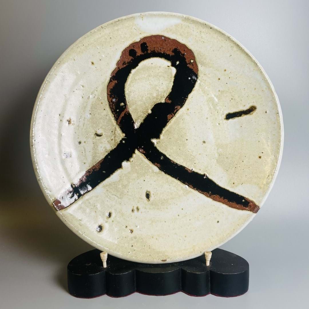 A ceramic plate glazed in dark brown and stone colour