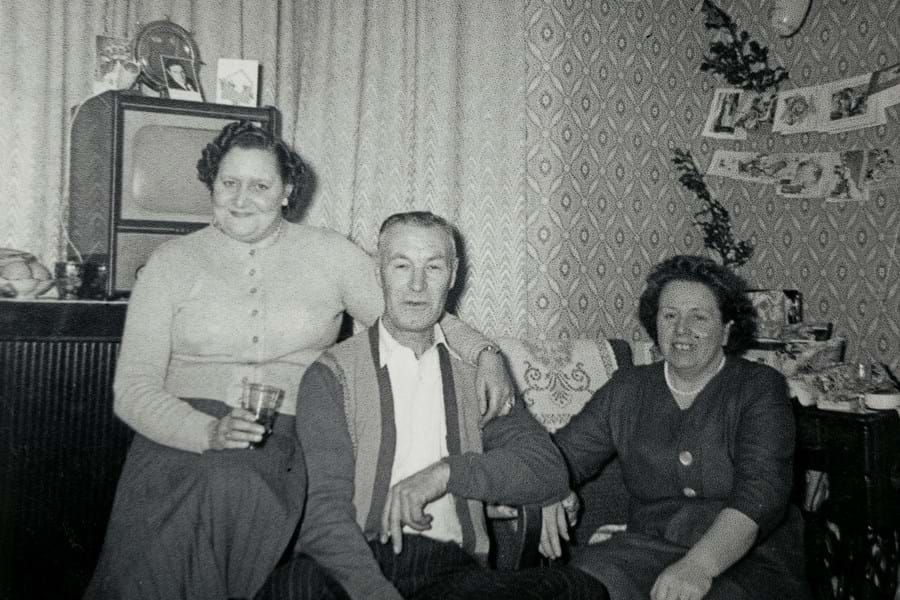 Black and white image of three people sitting together in front of a television set