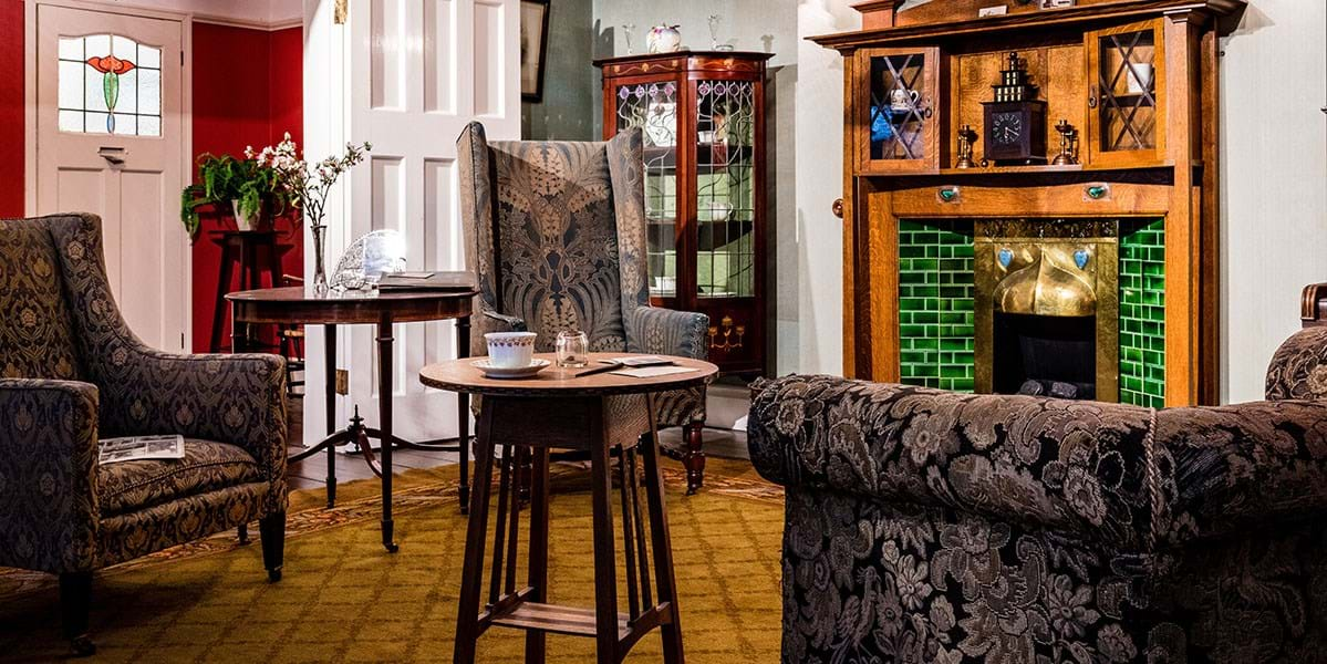 Sofa and two armchairs in a front room setting with green tiled fireplace