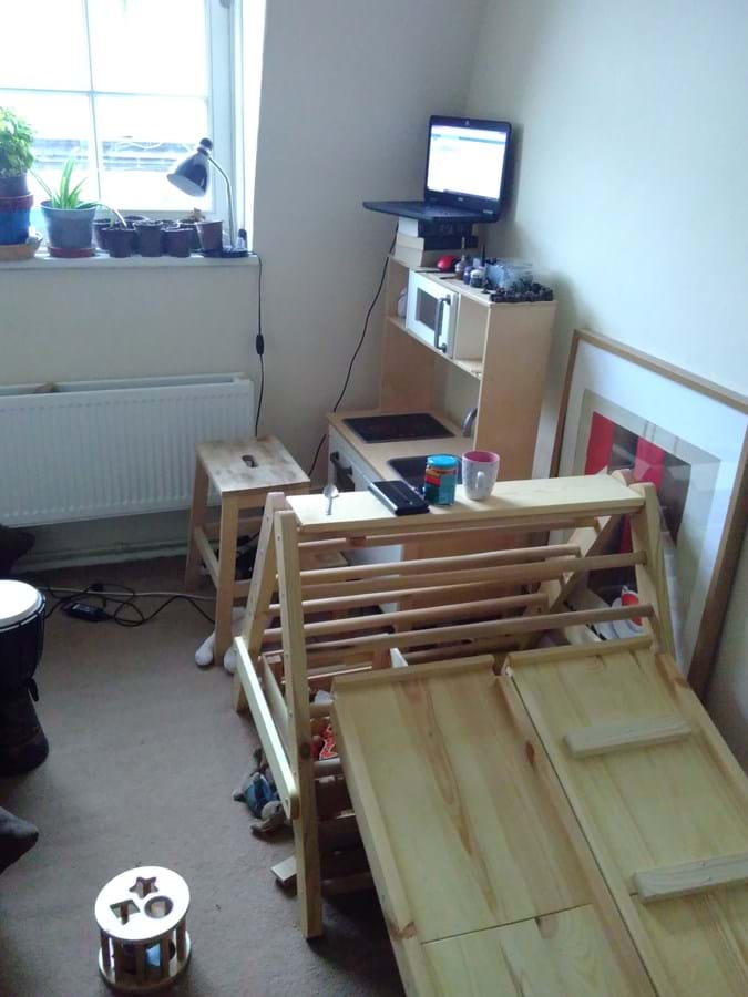 A computer on a shelving unit with a wooden structure in the foreground