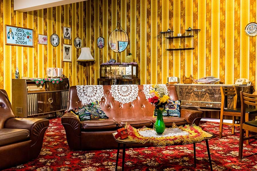 A room decorated with a red. flora carpet, yellow patterned wallpaper and a brown leather sofa