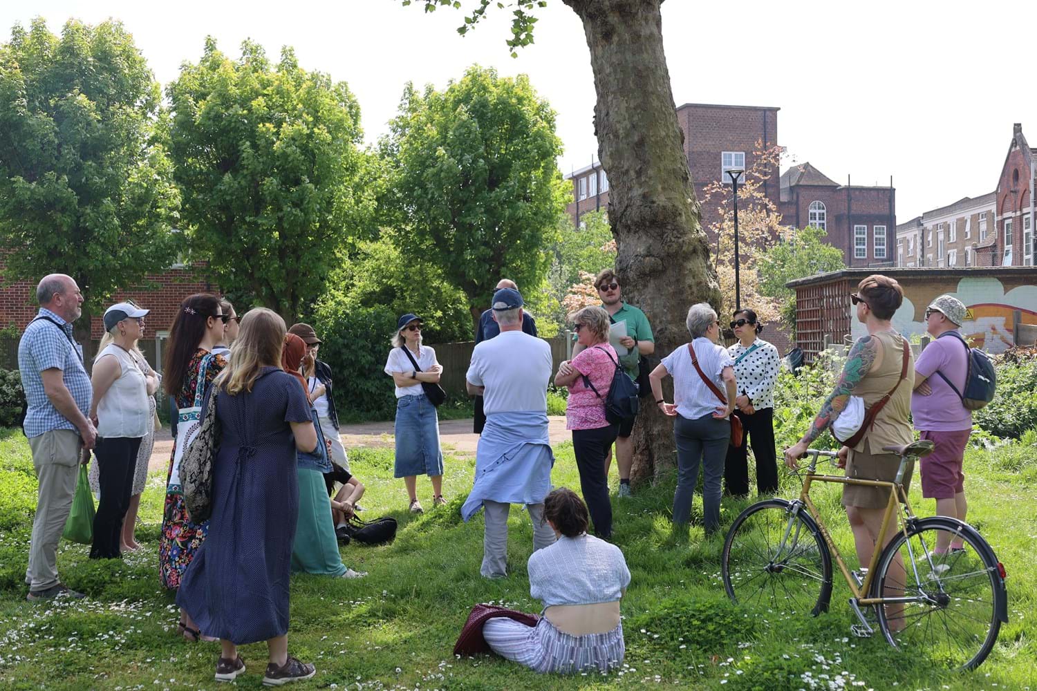 A group of individuals gathered around a tour guide in a park, enjoying the tour.