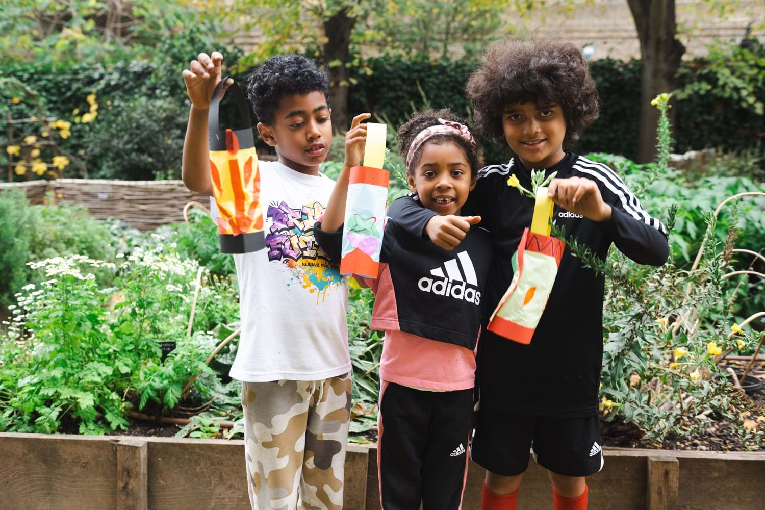 Three children hold up their handmade lanterns