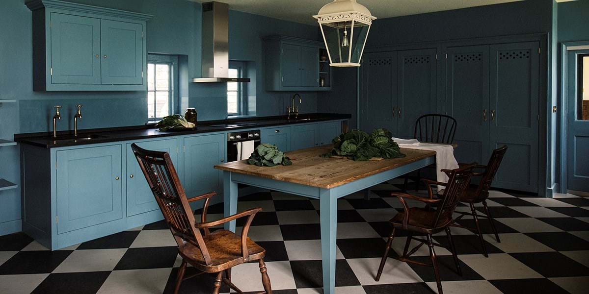 A blue kitchen with white and black checkerboard floor