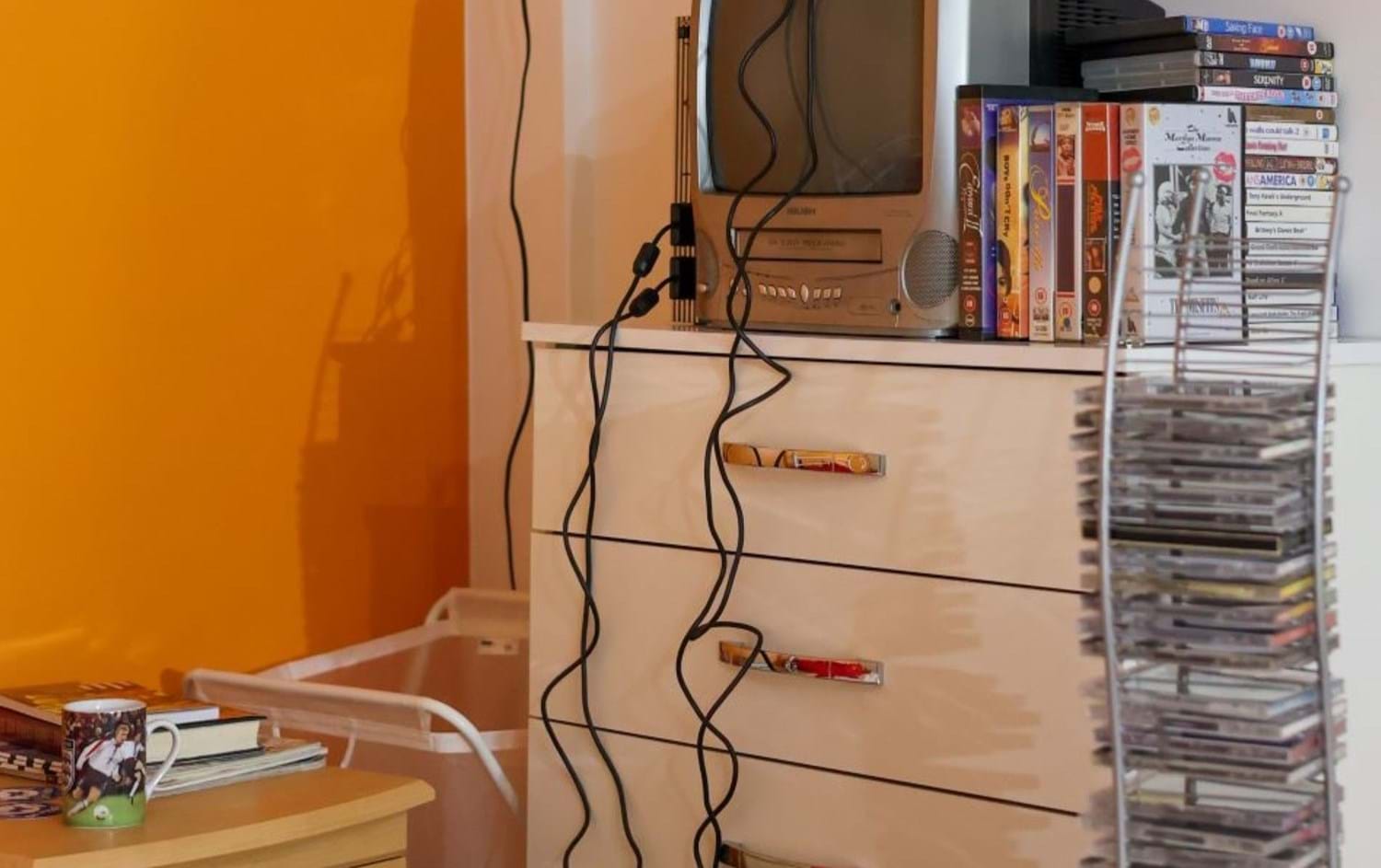 White dresser with TV on top, with videos and CDs next to it