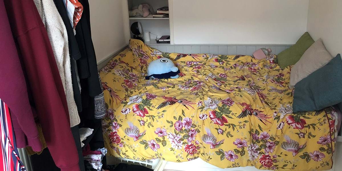 A bed with a floral duvet and various pillows