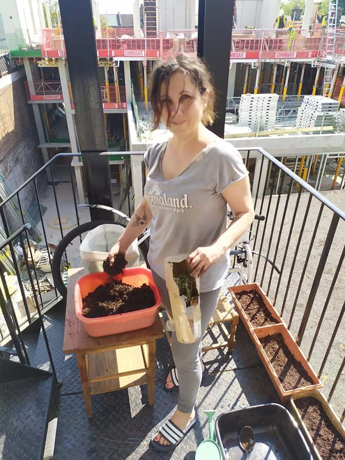 Person on balcony putting soil into pots