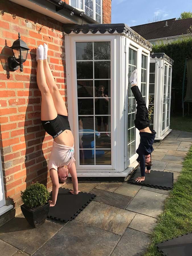 Two people doing handstands against the wall of a house