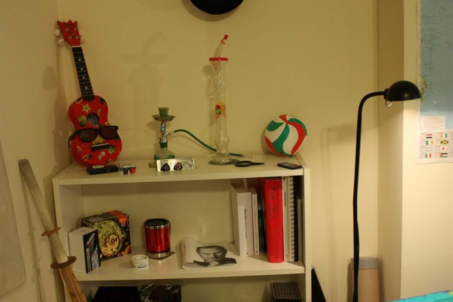 A white bookcase with books, cups, ornaments and a ukelele