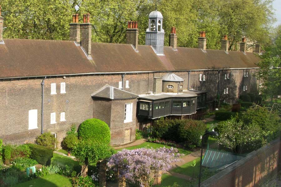 Aerial view of a large brick building with green gardens.