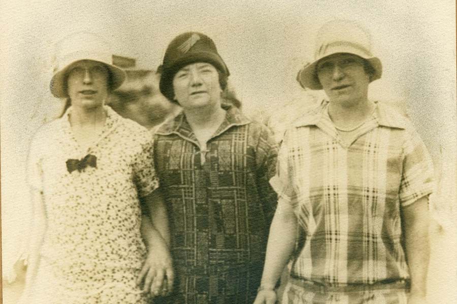 Sepia photograph of three adults wearing dresses and hats