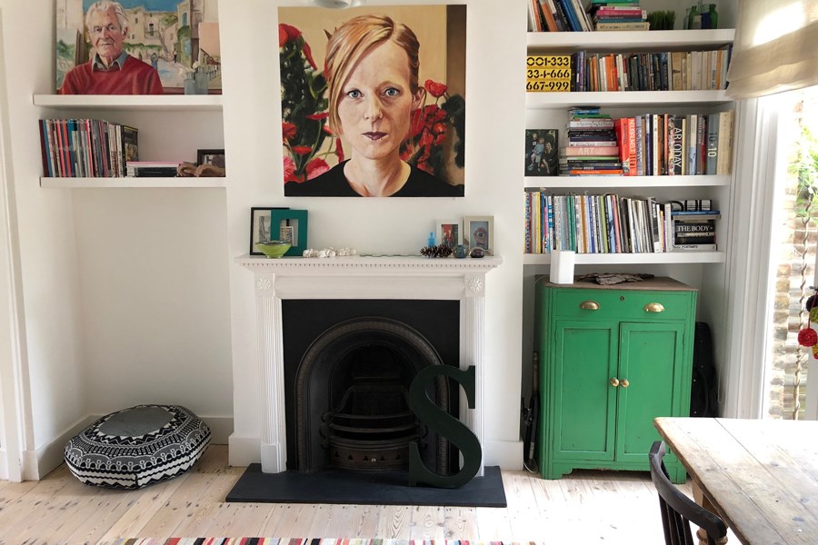A fireplace surrounded by bookshelves and paintings