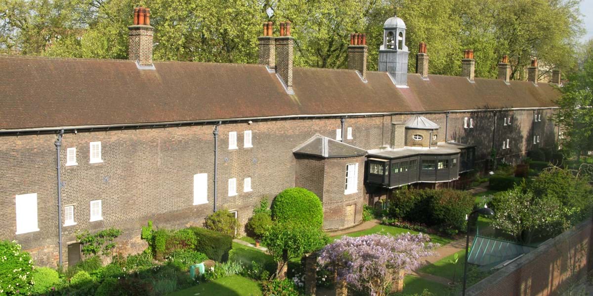 A large brick building set behind green gardens
