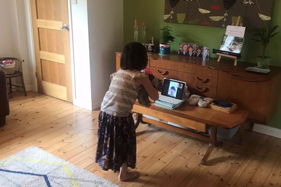 Child standing in front of laptop while doing a video call