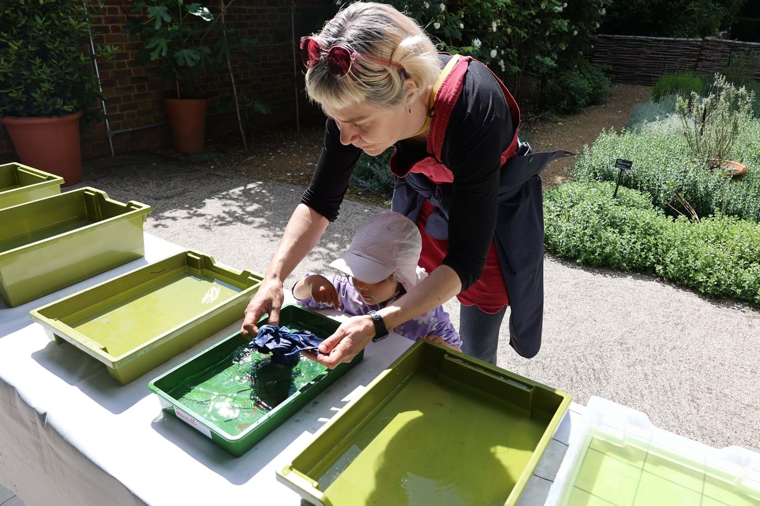 A child and a carer dyeing a piece of fabric in Garden Through Time at Museum of the Home.