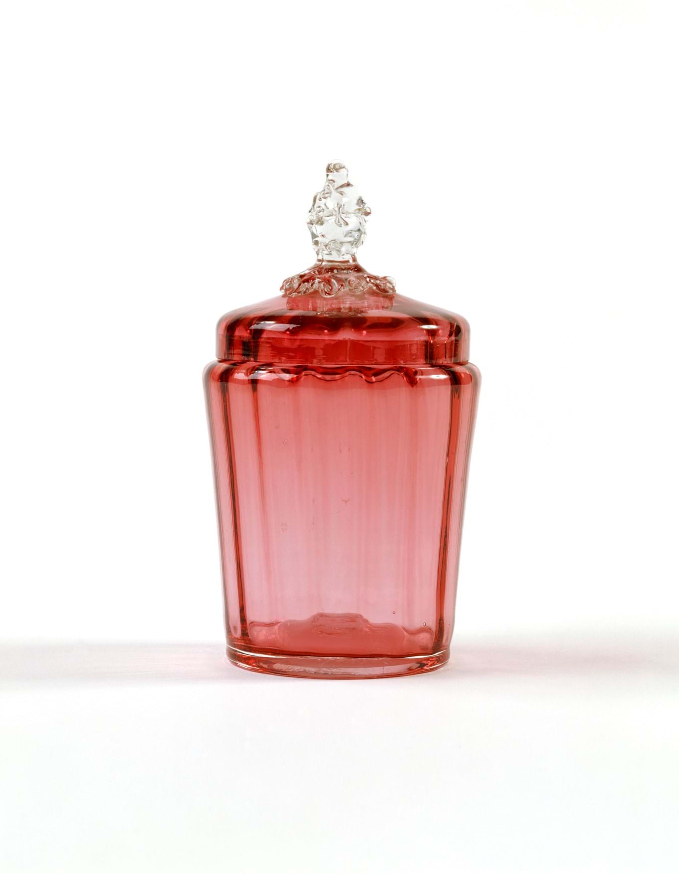 Cranberry-coloured glass jar with a ribbed interior and lid 