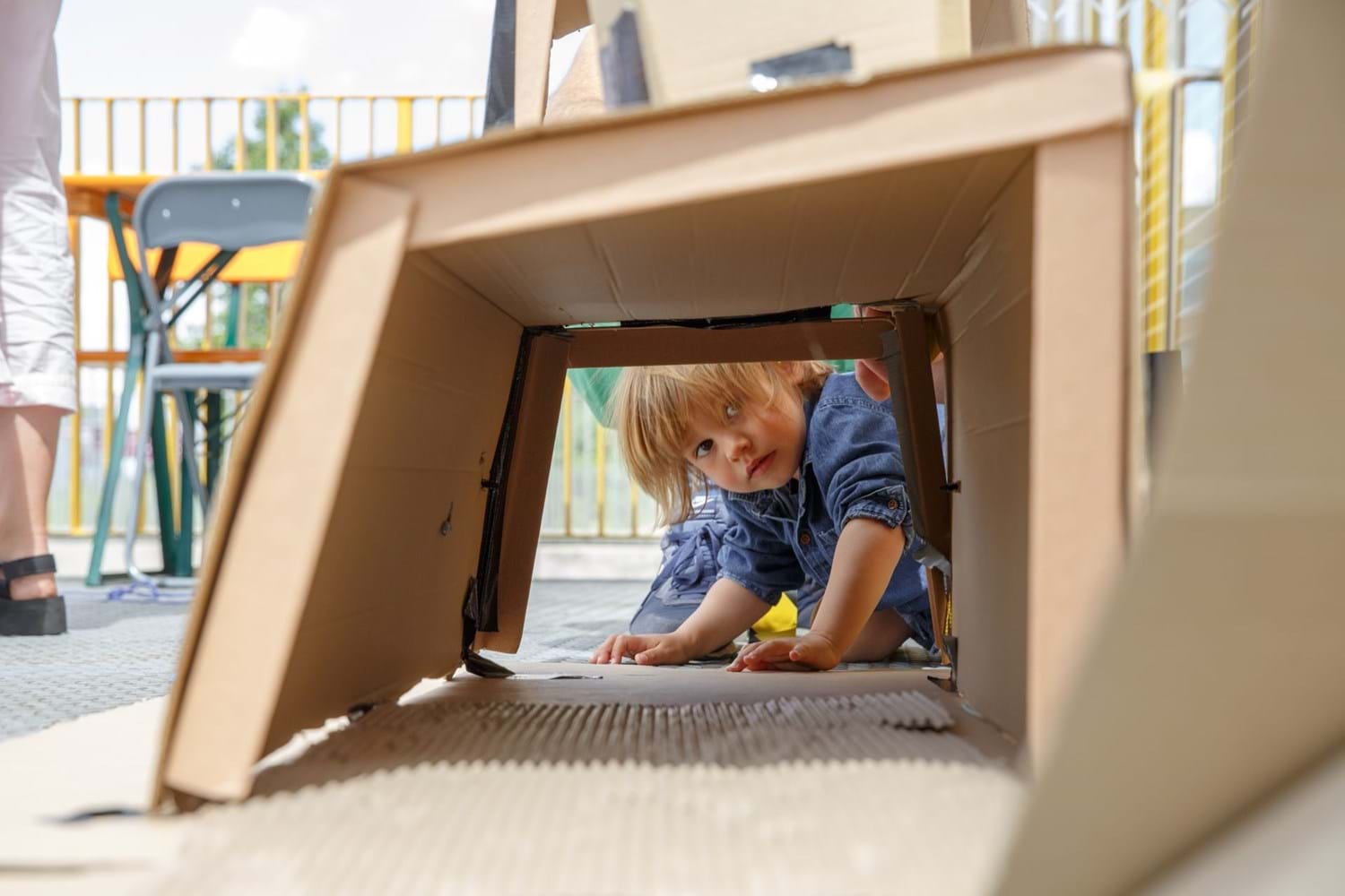 A child peers through a wooden play structure
