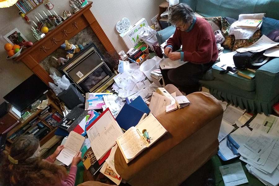 Two people sitting on the floor of a room surrounded by papers