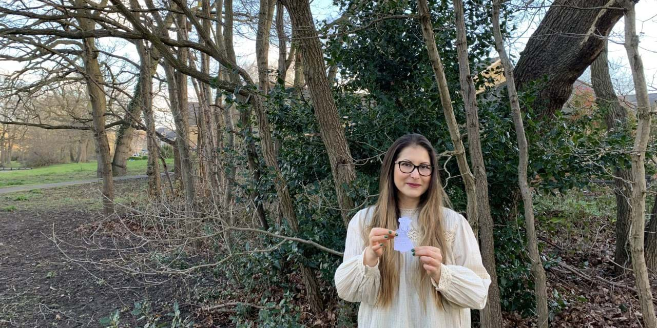 A person holding a piece of paper standing in front of a tree