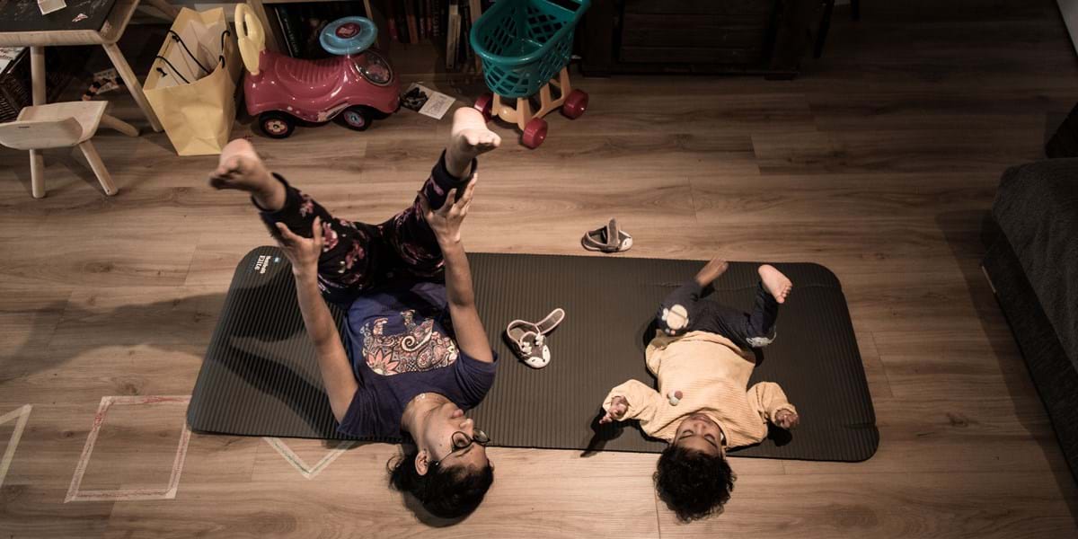An adult and a small child laying on an excercise mat