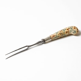 A metal two-pronged fork with a cream handle, decorated with colourful patterns