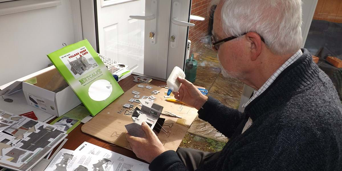 A person sat at a table putting together a model building