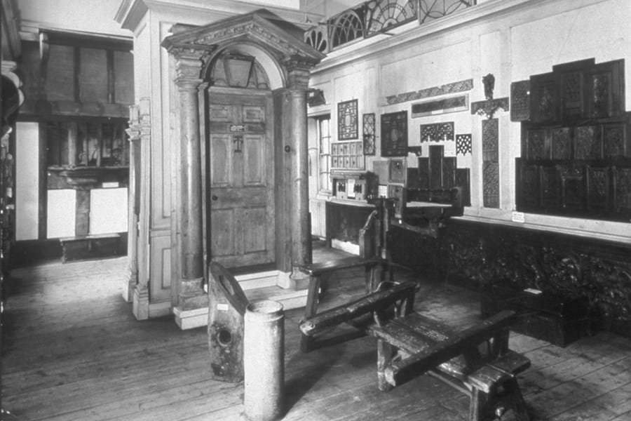 A black and white photo of a room in the Museum of the Home with various wooden items displayed
