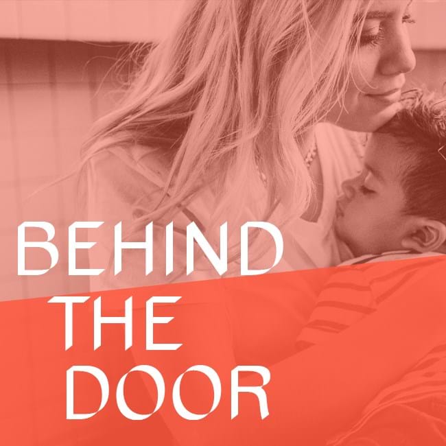 A person holding a baby, with text overlaid that reads 'behind the door'