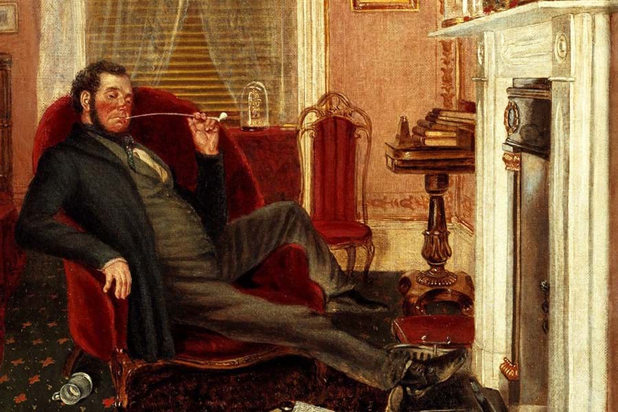 A person sat on a red armchair, smoking a pipe with feet by the fire
