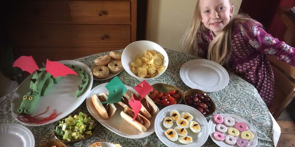 A child posing with a selection of party food spread across a table 