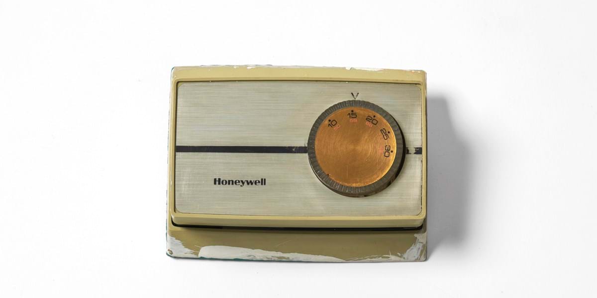 A beige thermostat on a white background