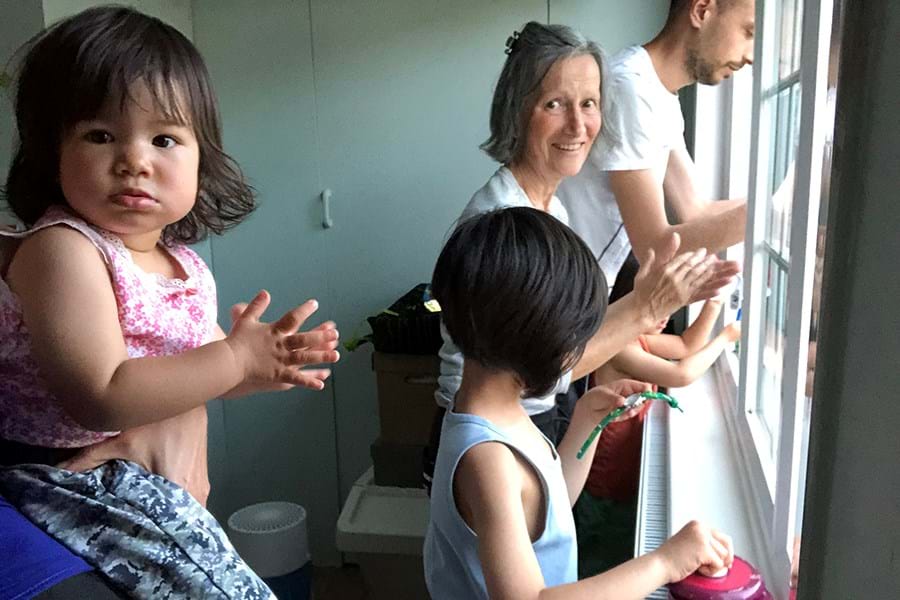 Children and adults clapping at a window
