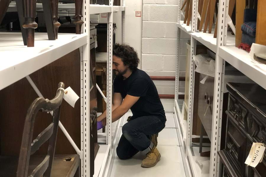 A person rearranging objects in the museum stores